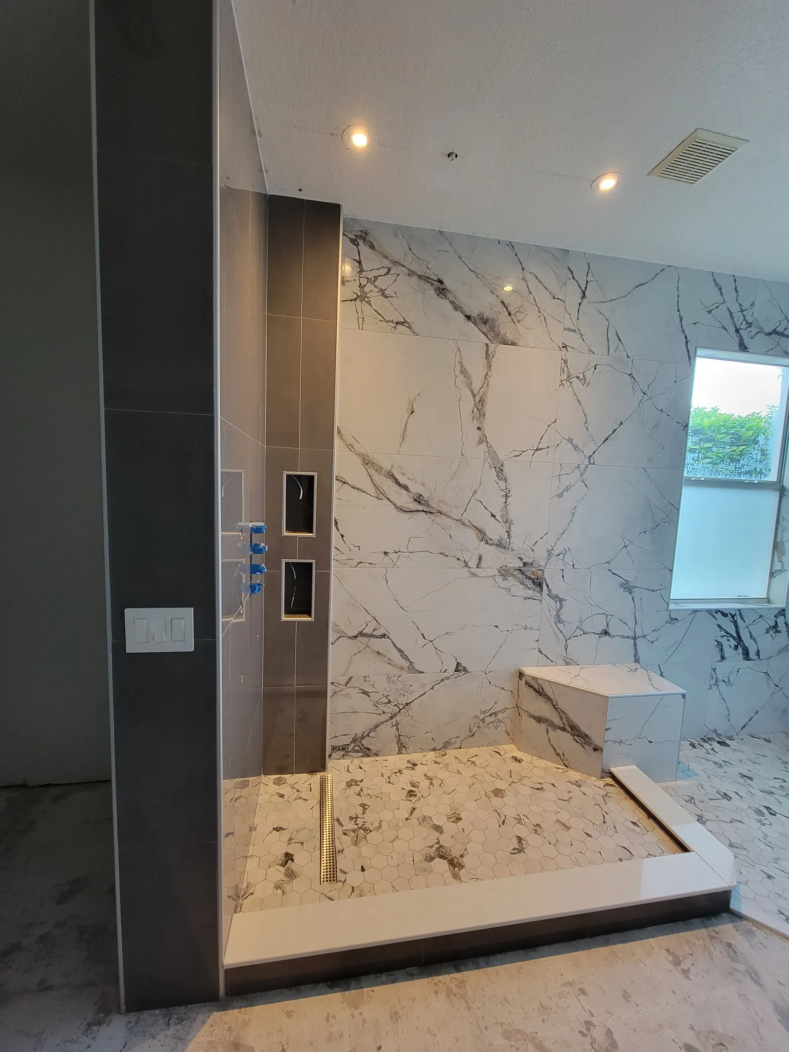 Finished shower with marble-look porcelain, charcoal accent wall and bench