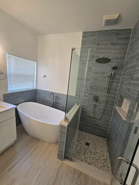 Master bath with freestanding tub, frameless glass walk-in shower and grey plank-look tile