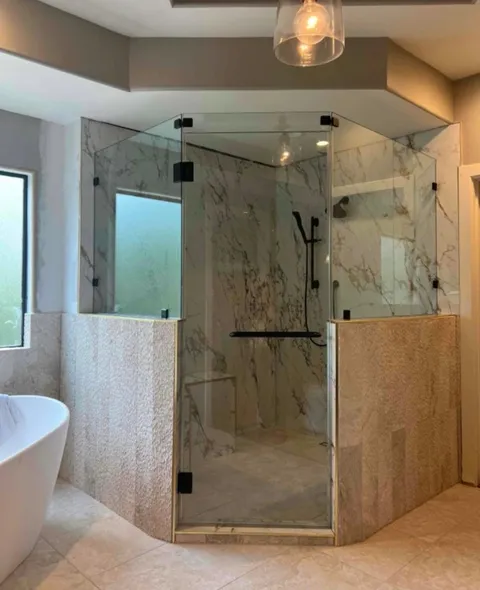 Marble-look neo-angle shower with frameless glass beside a freestanding tub