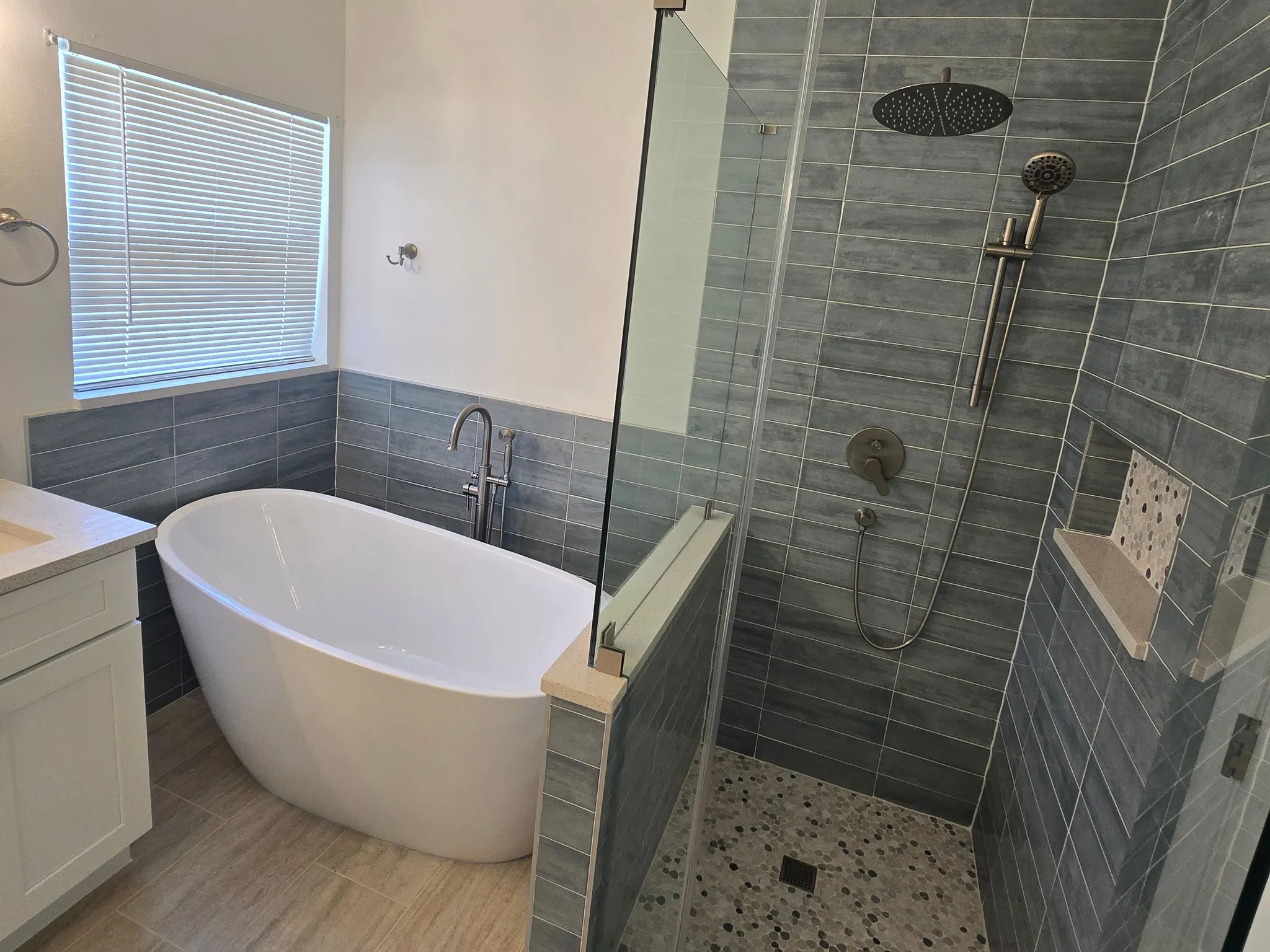 Master bathroom with freestanding tub and a frameless glass walk-in shower in grey plank-look tile
