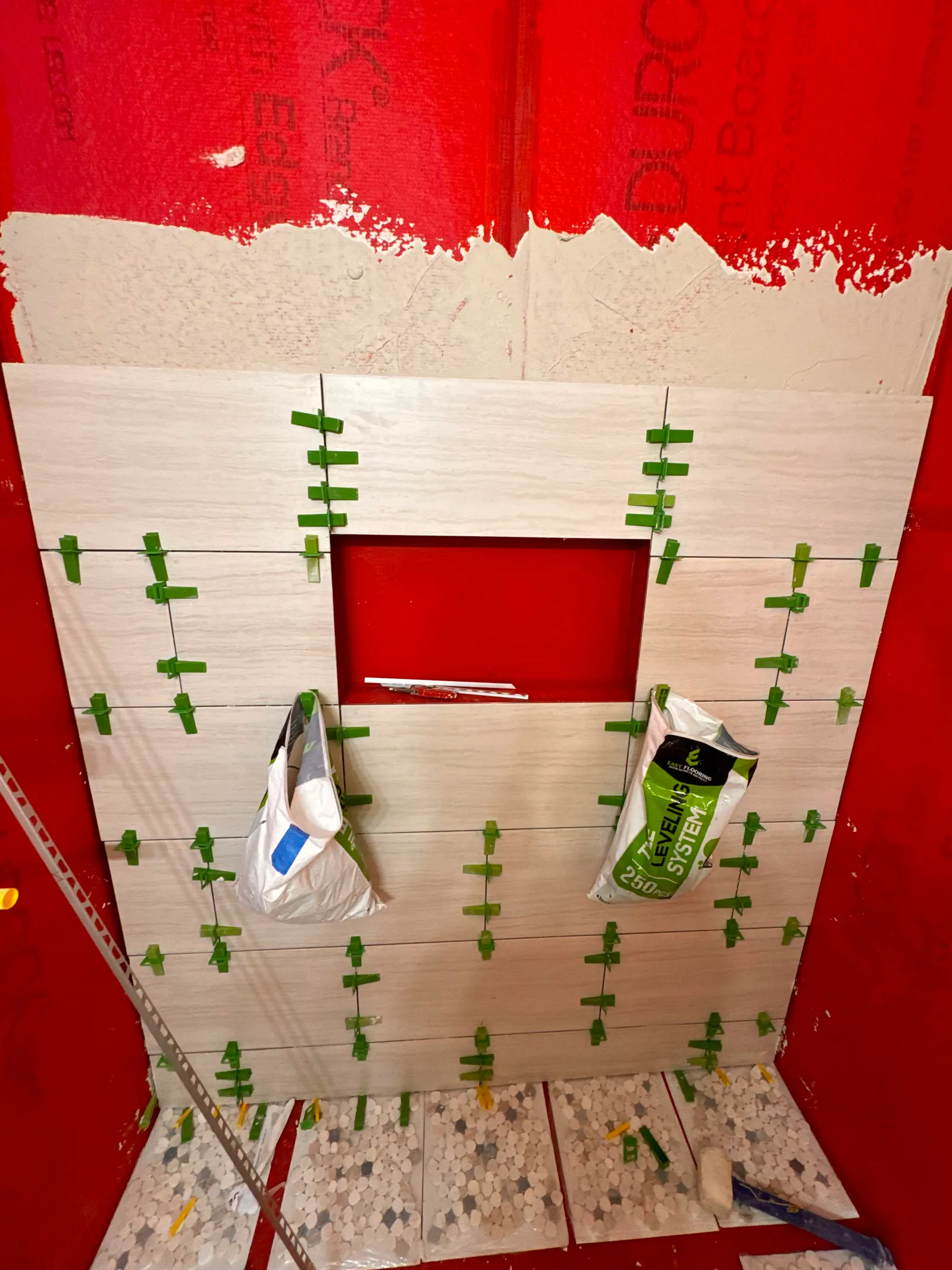 First rows of light stone-look tile going up over the red membrane with leveling clips