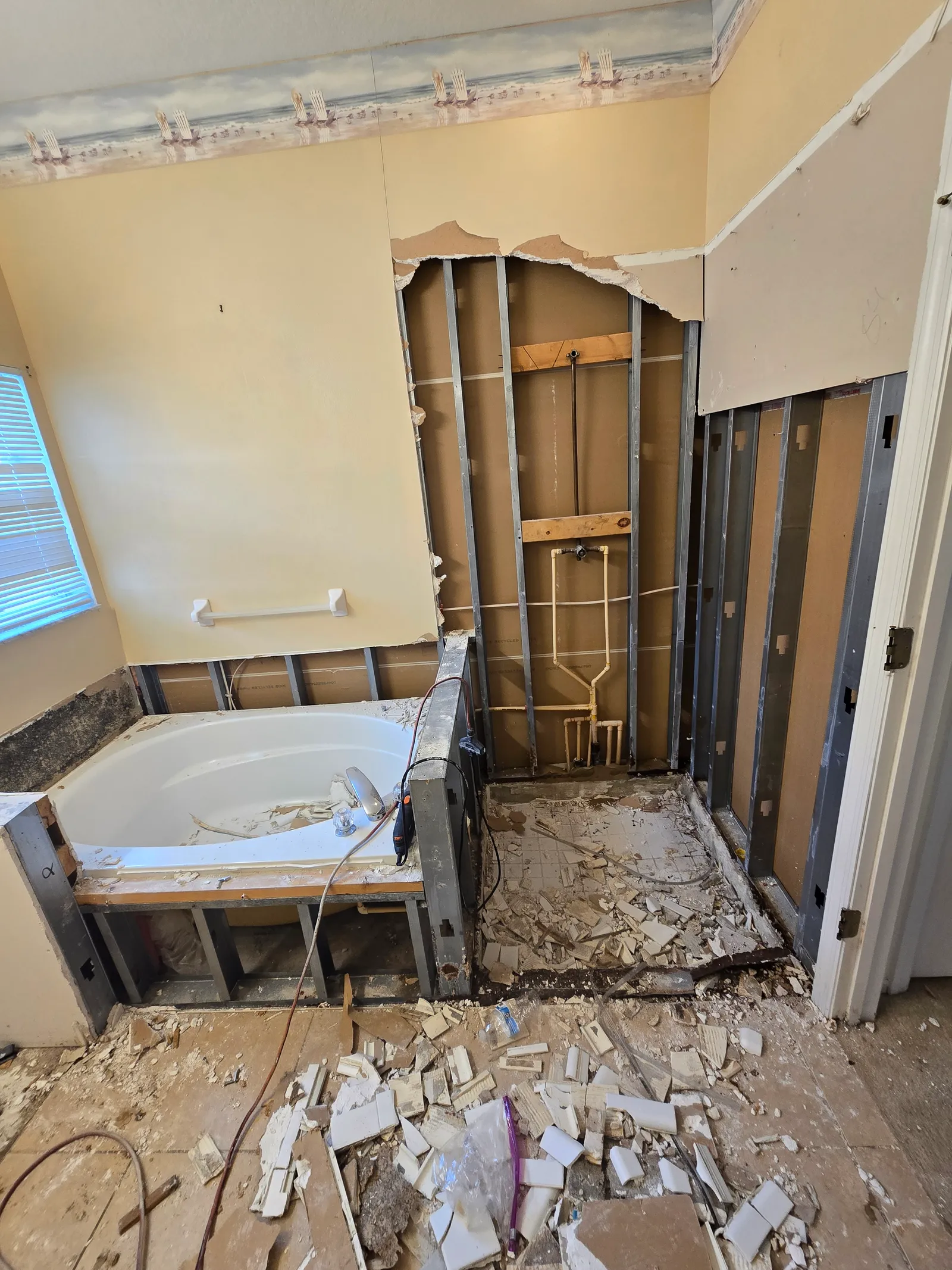 Master bath demolished: old tub deck exposed and shower wall opened to the studs